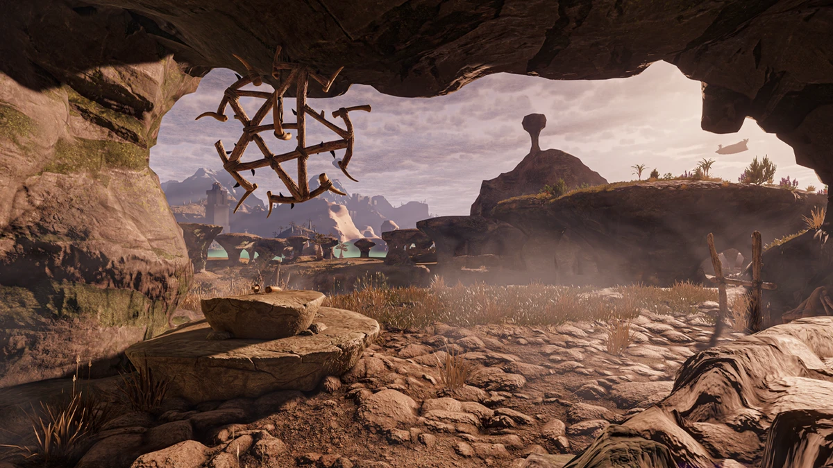 A clear 16:9 fantasy landscape viewed from a rocky cave, with rugged terrain, distant ruins, unusual rock formations, and warm atmospheric lighting.